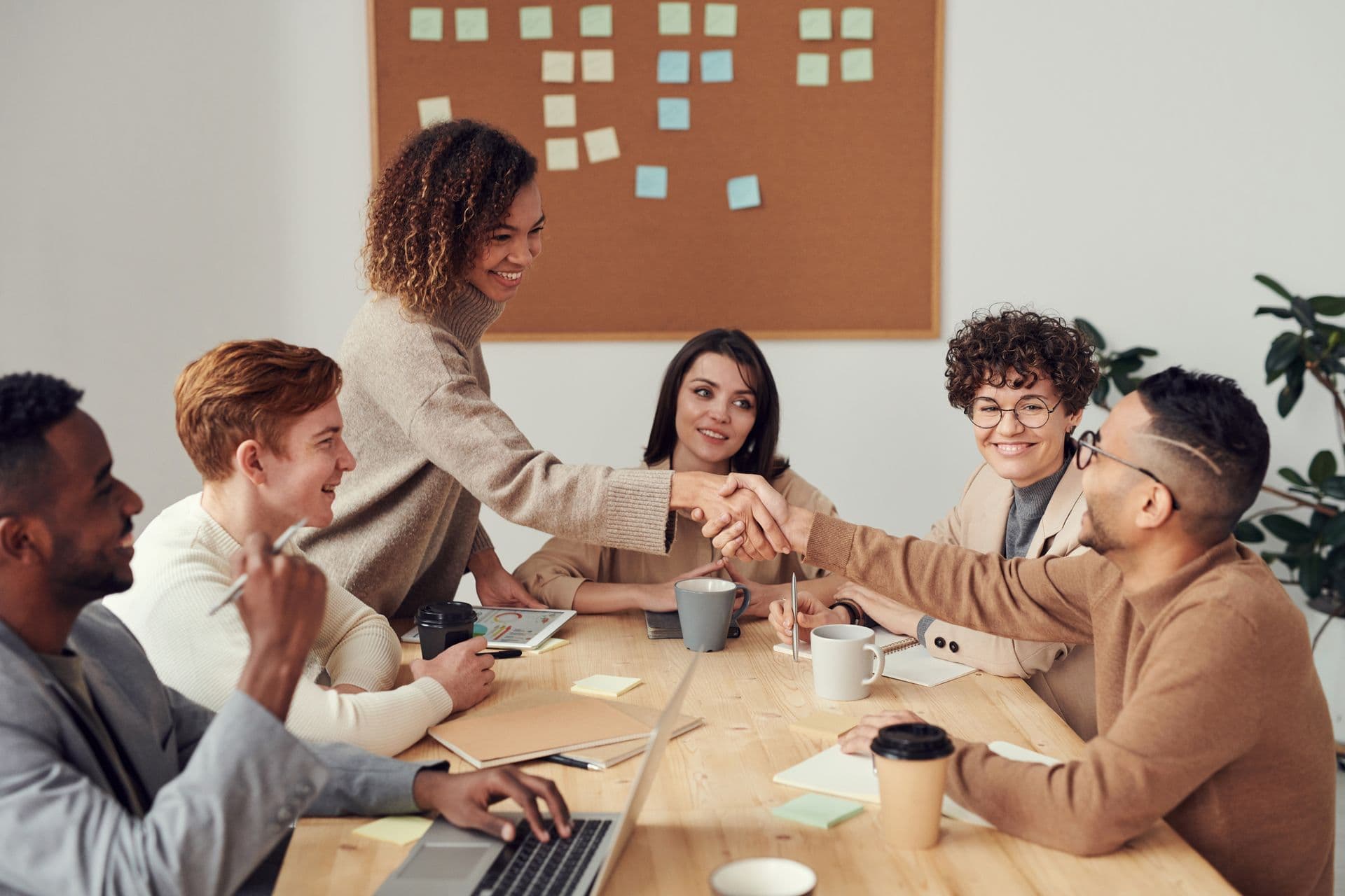 Hiring team shaking hands with a candidate across a meeting table