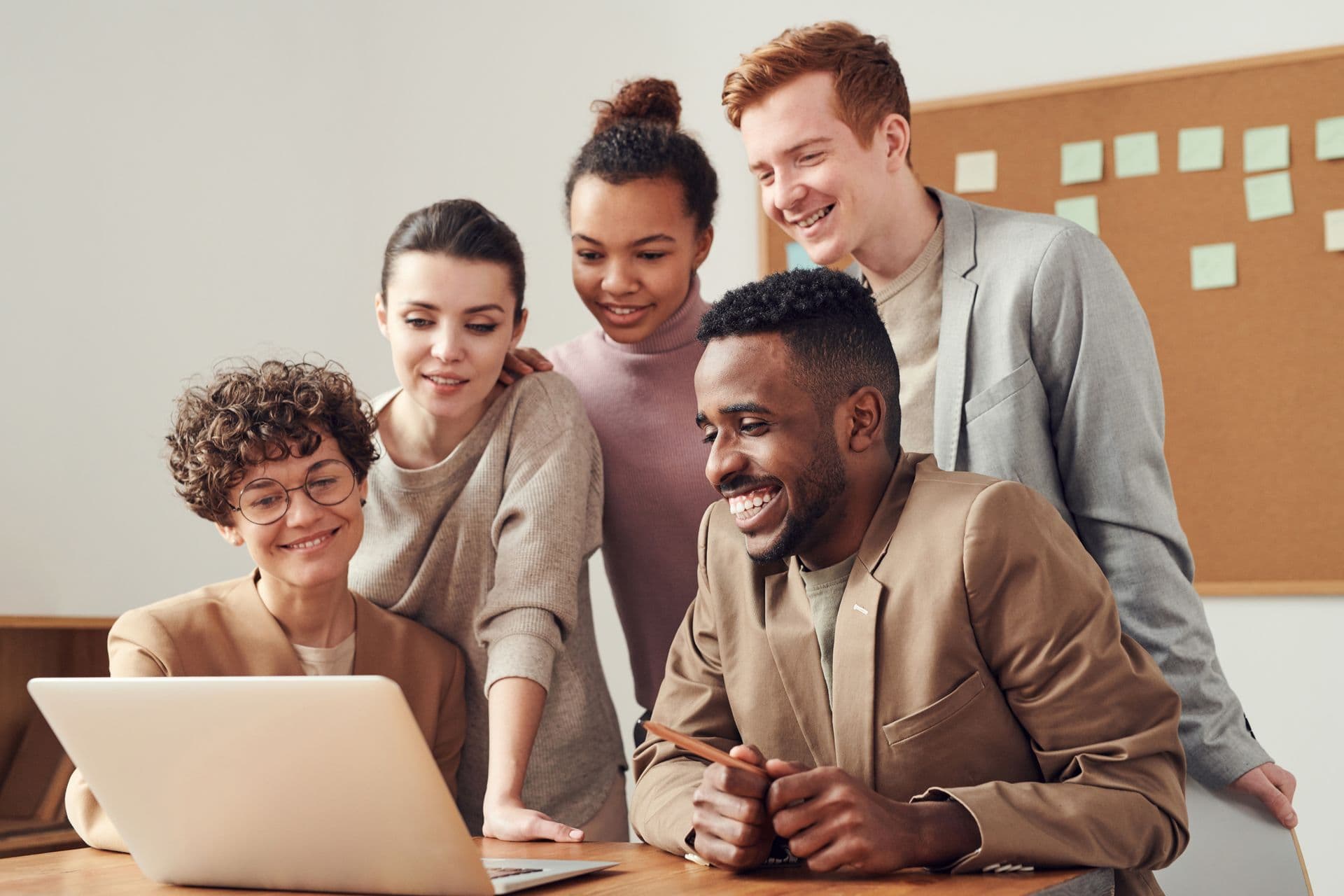 Colleagues smiling together around a laptop in the office